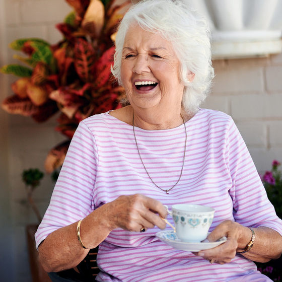 elderly woman with a cup of tea smiling