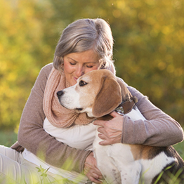 woman sitting outside on a sunny day hugging a dog
