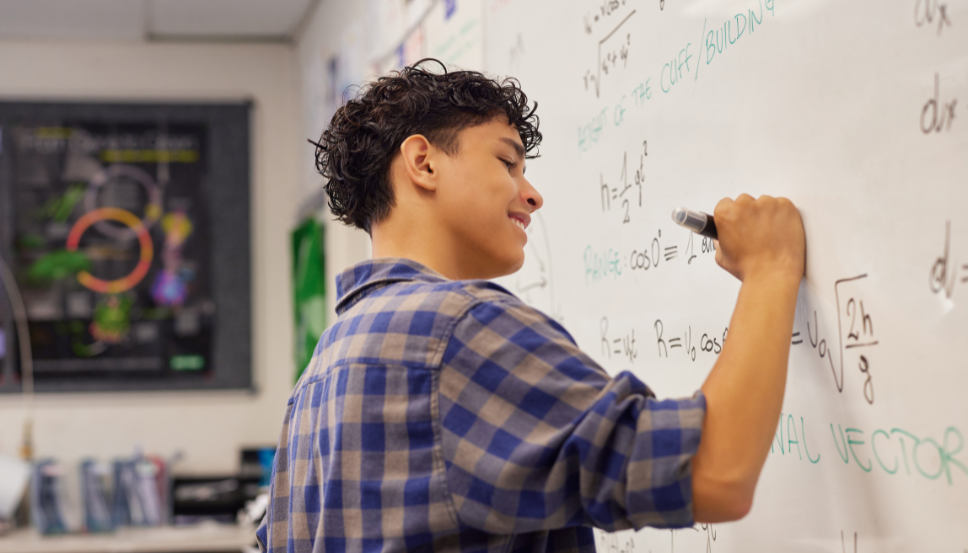 STEM Calculator Hero Image.png Teen boy doing math problem on chalkboard