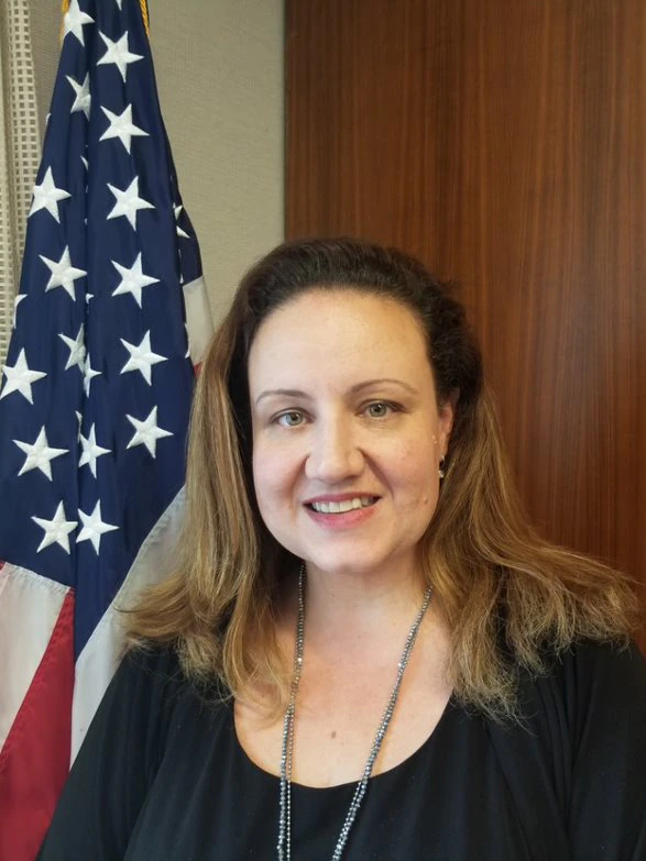 Ms Fotovat is smilling in front of an American flag.