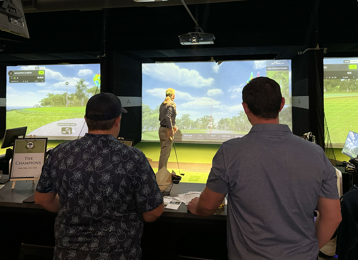 Photo of two men looking at a golf simulator screen.