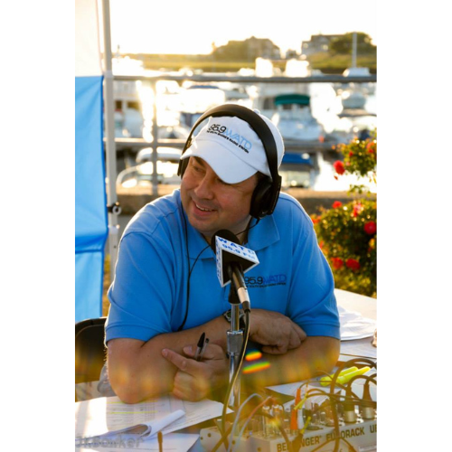 Rob Hakala of WATD behind a microphone with a white hate.