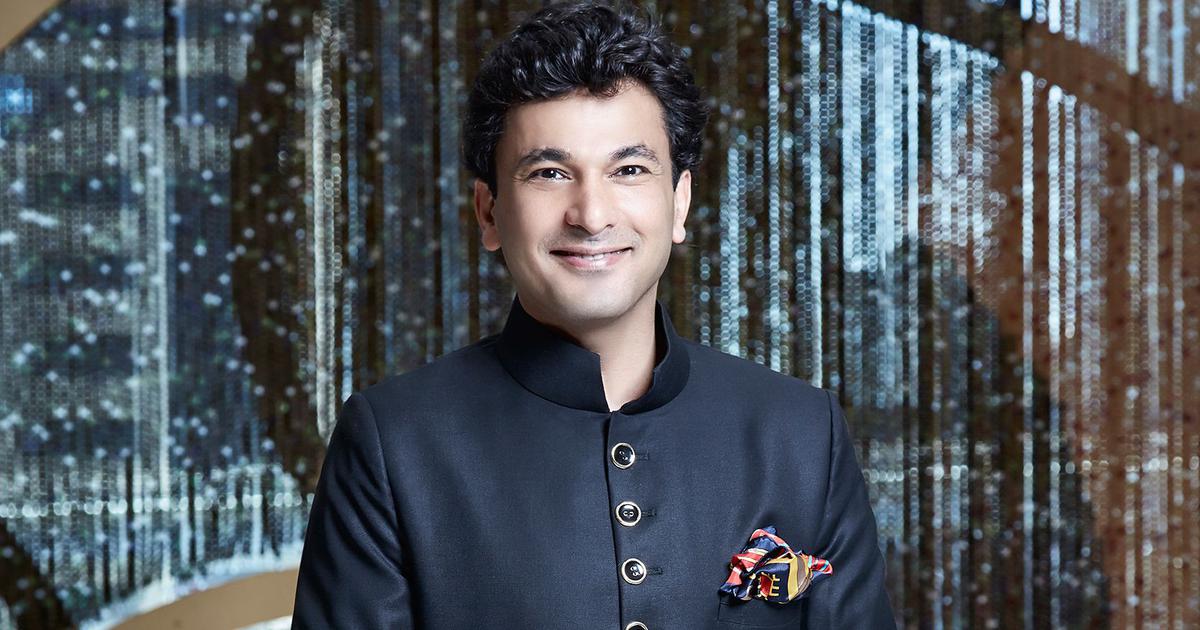 Vikas in a dark blue jacket, has his arms crossed and is smiling at the camera