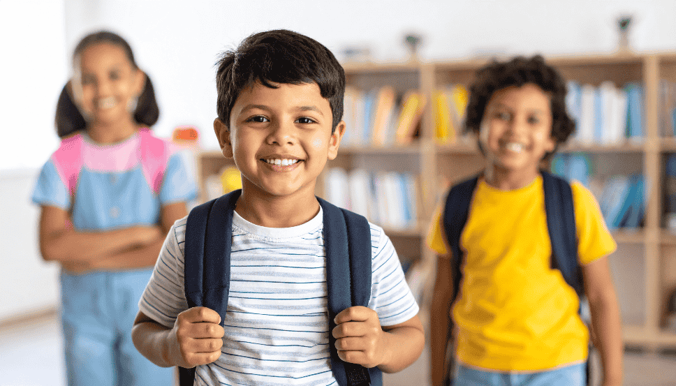 BTS 2026 Stock Image 164KB.png School children with school backpacks smiling in the hallway.