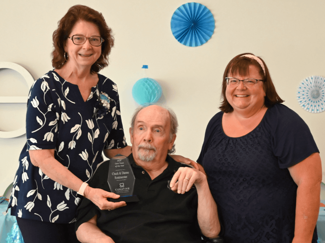 Dianne, Chuck, and Valerie posing together while Dianne holds an award