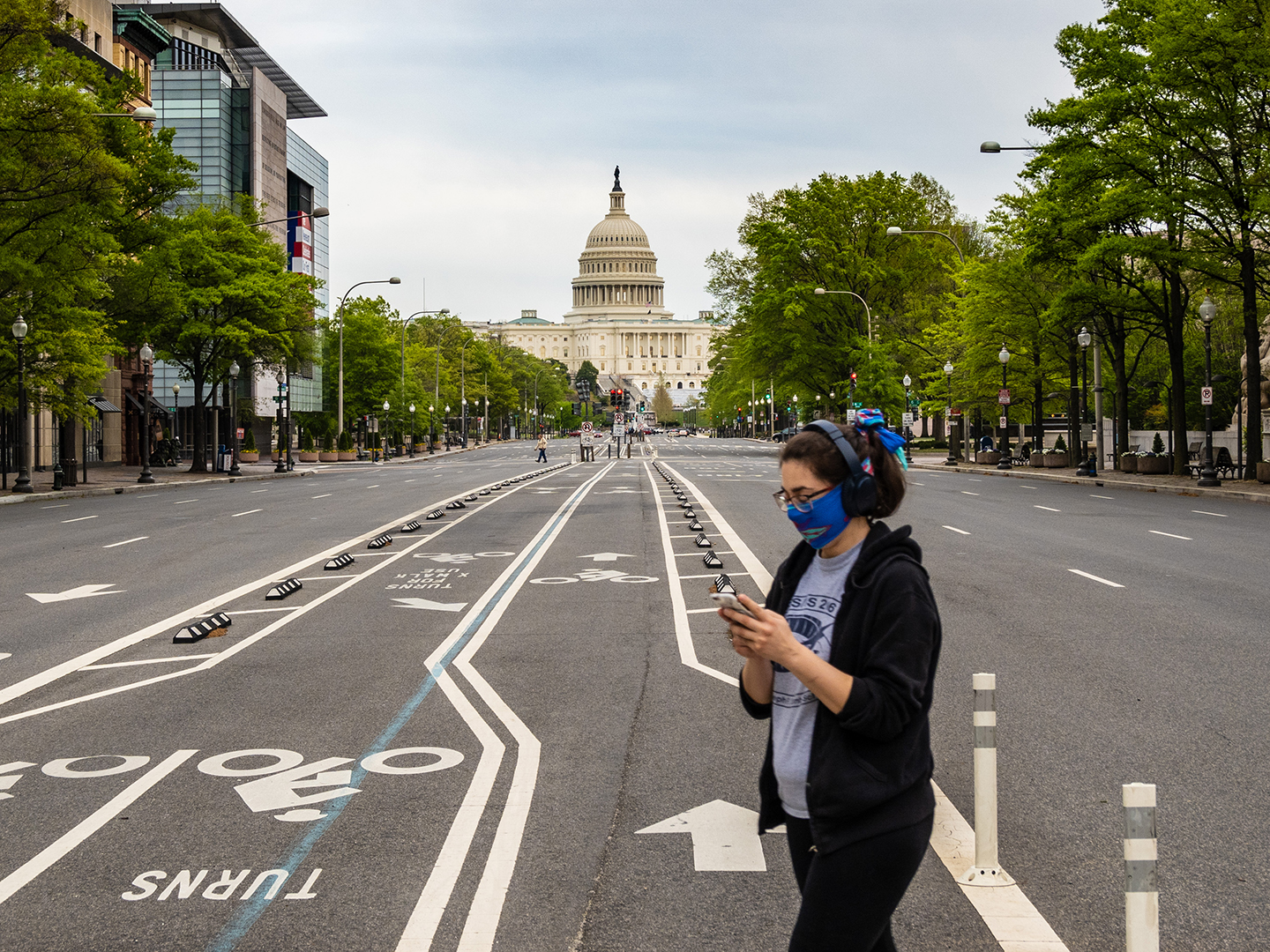 A person in a face mask walking by the United States Capitol Building