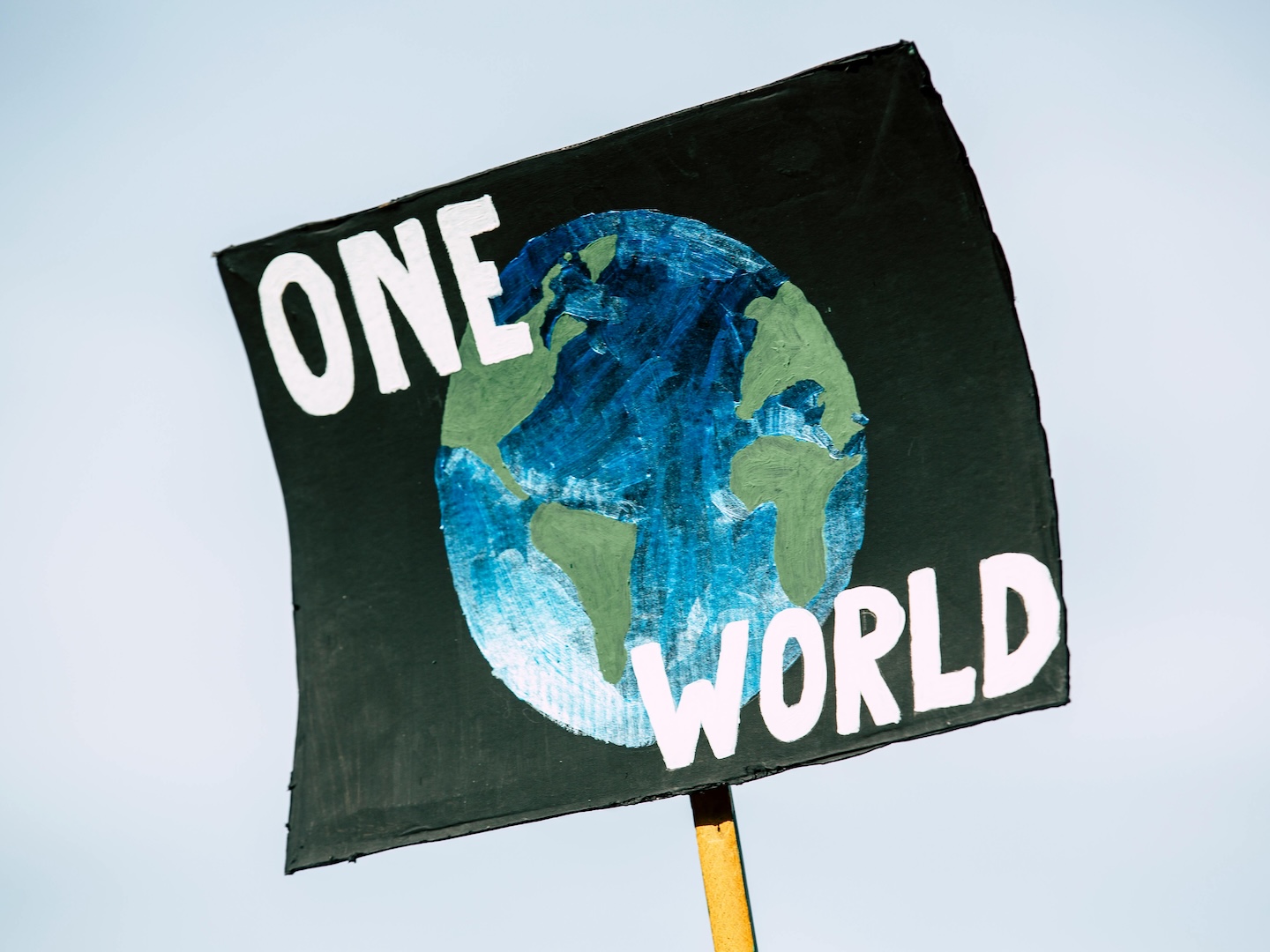 Poster with a painted image of a globe and text that reads "One World"