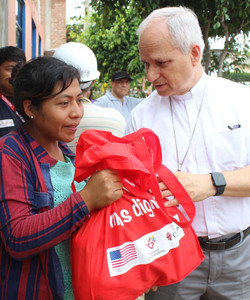 Bishop Robert Prevost, now Pope Leo XIV, handing a bag of food to a person affected by flooding in Chiclayo, Peru