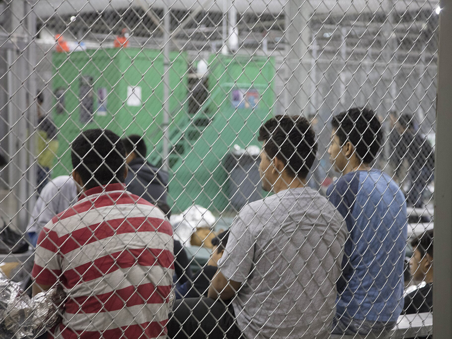 Three teenage boys sit in an immigration detention center.