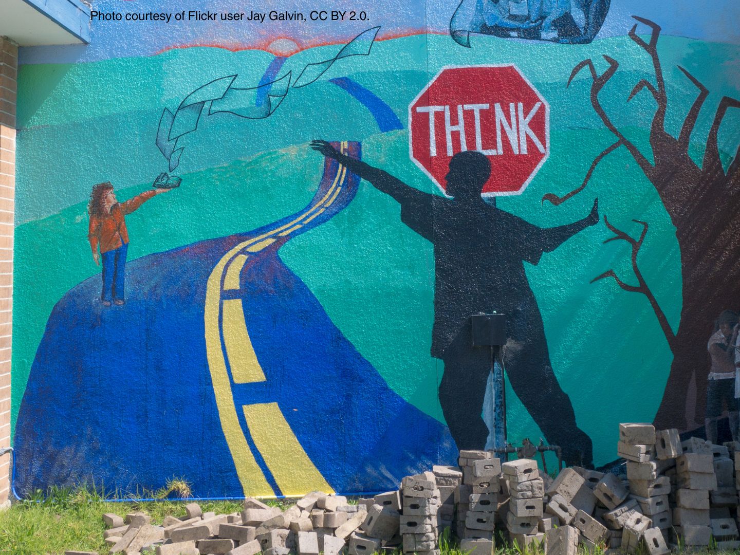 A colorful mural showing a person in front of a stop sign that says "think" and a girl with a book.