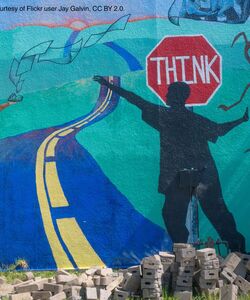 A colorful mural showing a person in front of a stop sign that says "think" and a girl with a book.