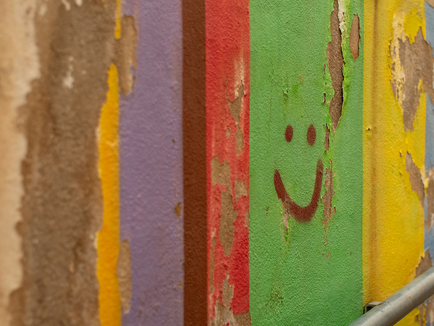 Wall painted with multiple bright colors and a smiley face