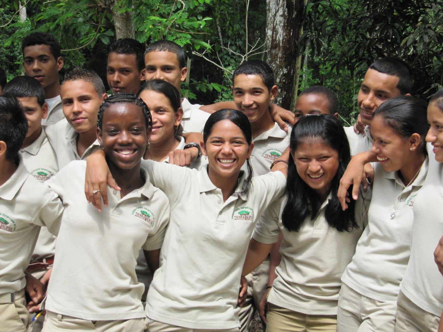 A group of a dozen young people arm in arm and smiling at the camera.