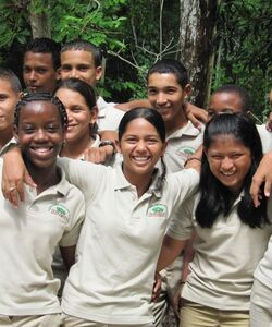 A group of a dozen young people arm in arm and smiling at the camera.