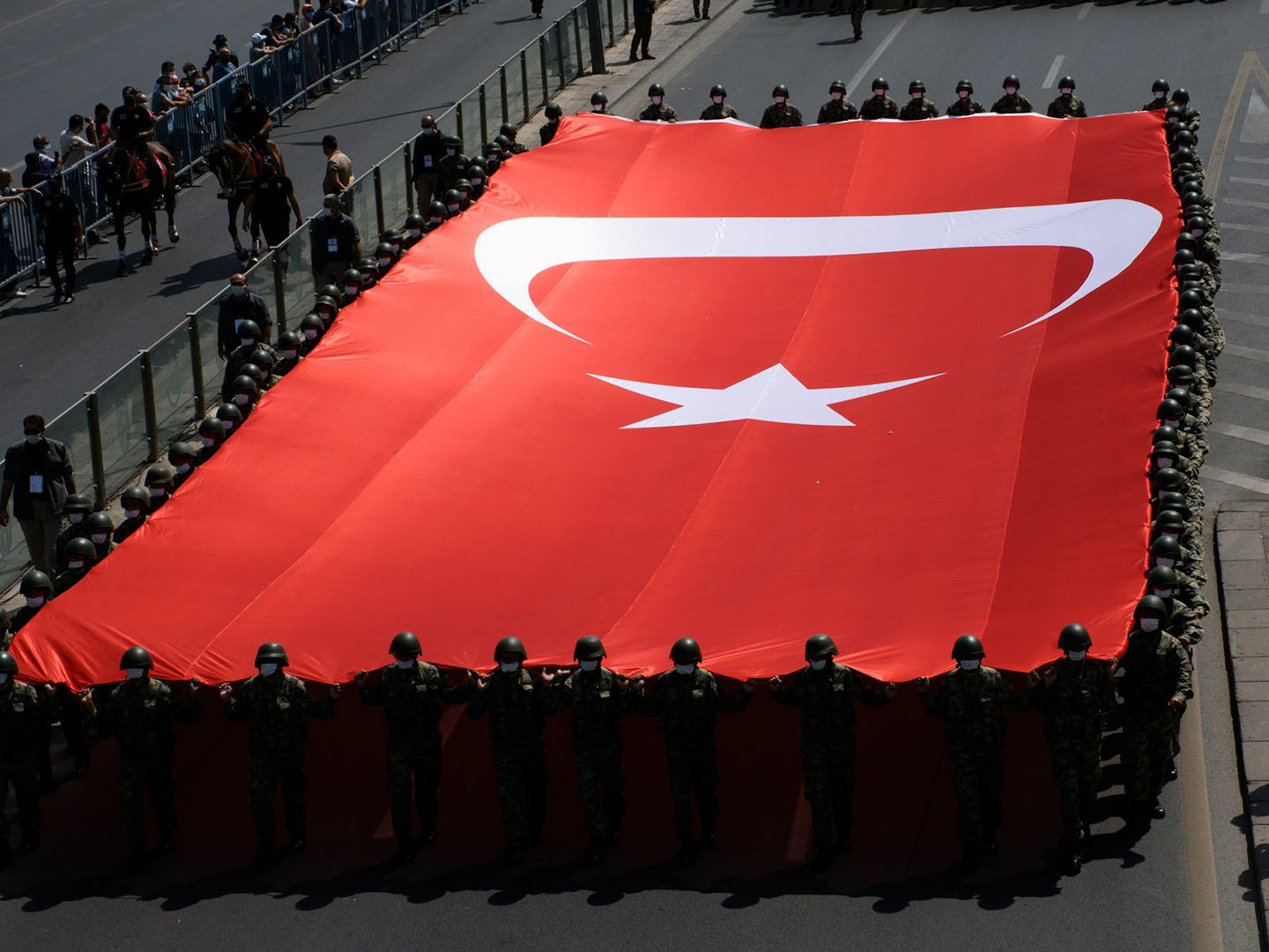 Parade with soldiers holding a giant Turkish flag