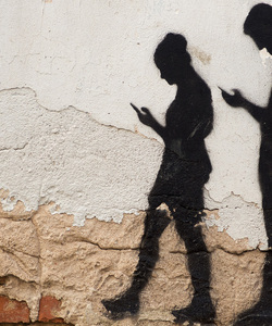 Street wall art of pair of young people walking while looking to mobile phone screen