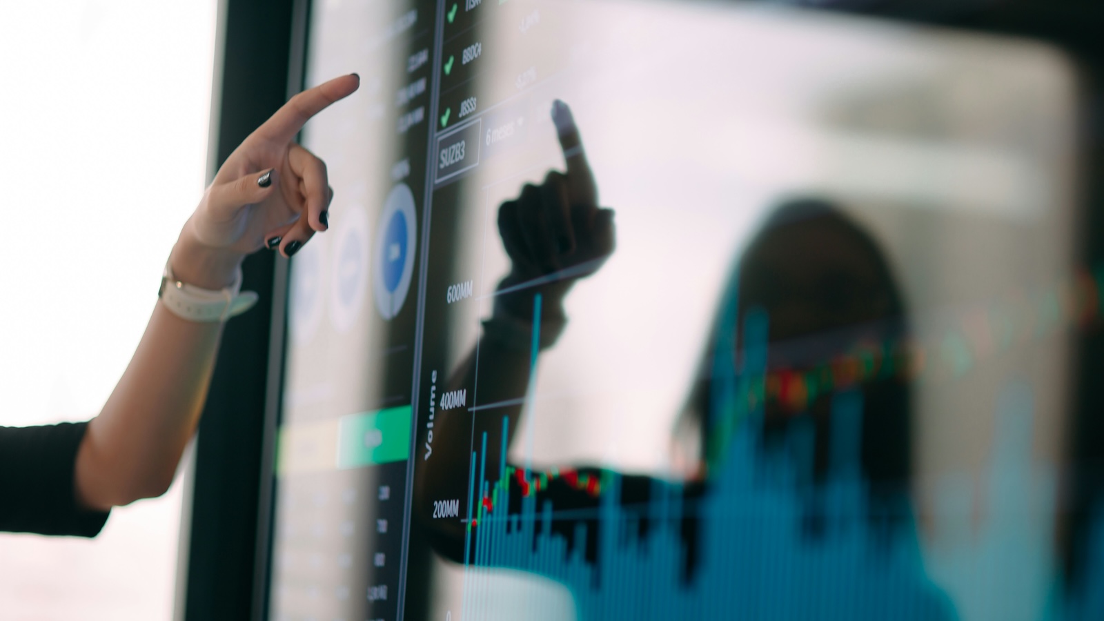 A hand reaches out to touch a screen with graphs and numbers