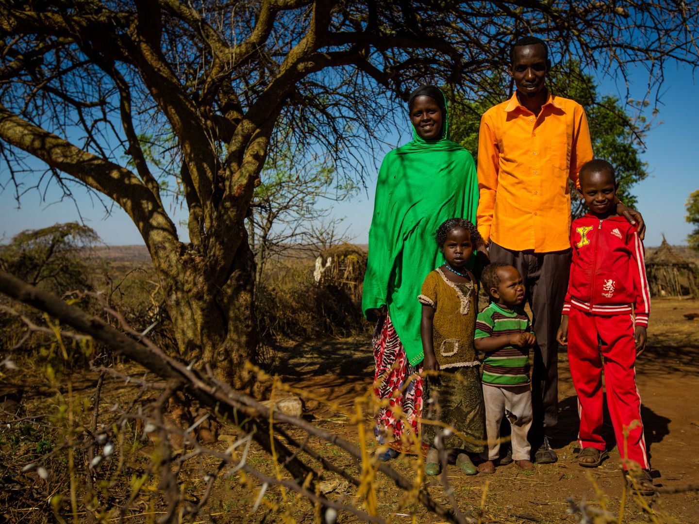 A family of five stands together in front of a tree in Ethiopia.