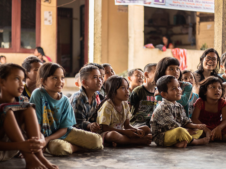 Elementary school-aged children in Indonesia smile at a presentation.