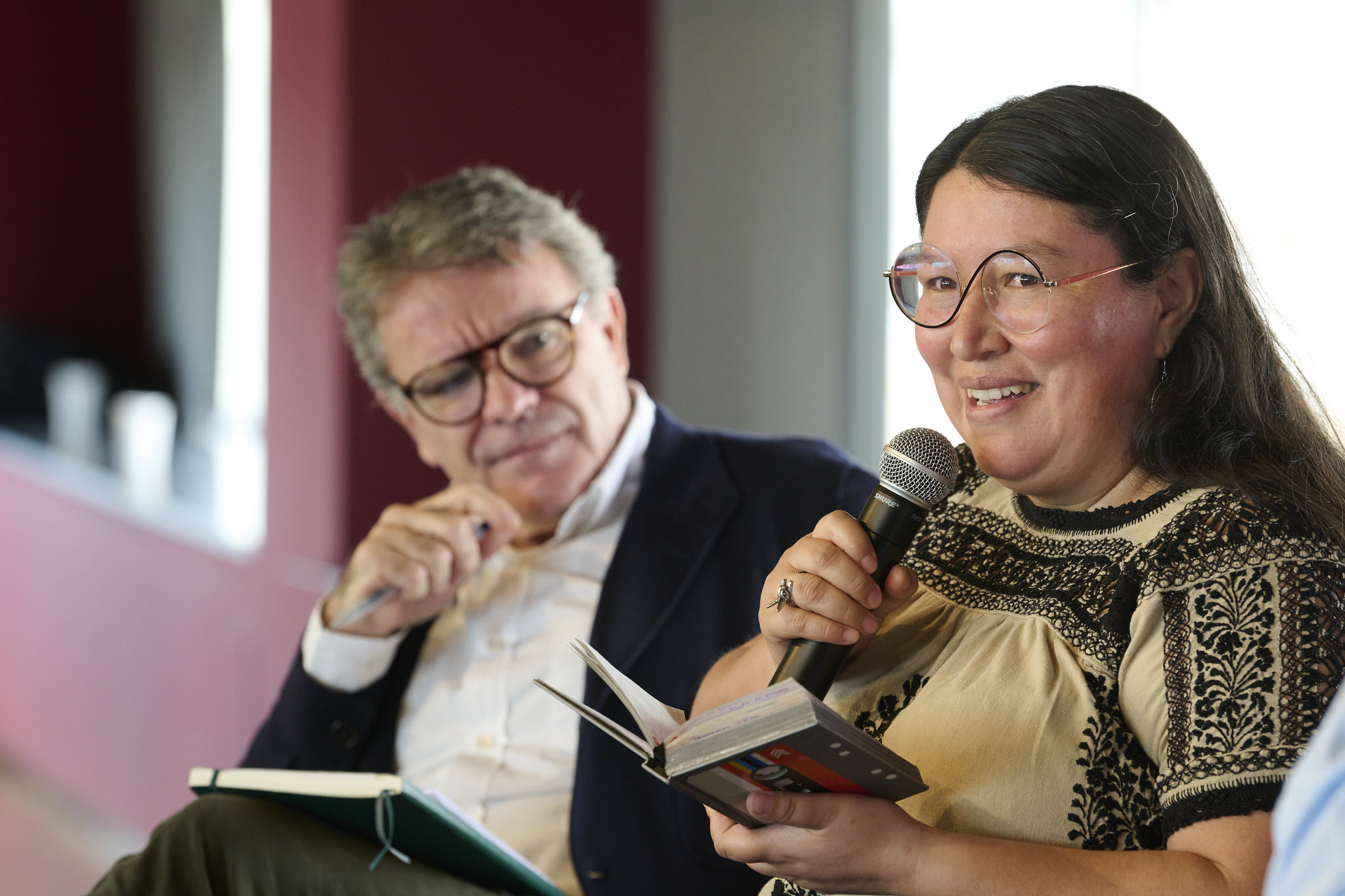 Yásnaya Elena A. Gil speaks into a microphone while Rafael Vilasanjuan looks on.
