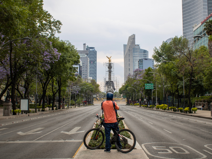 A panoramic of an empty Paseo de la Reforma in Mexico City and a person in a bike