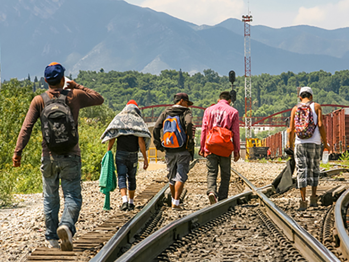 People walking down train tracks with their backs facing the camera