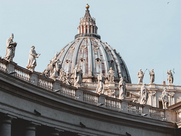 The dome of Saint Peter's Basilica behind statues