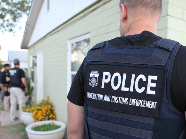 ICE agent standing outside of a house