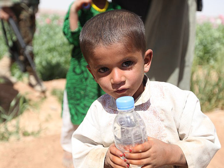 An Afghan child holding a bottle of water