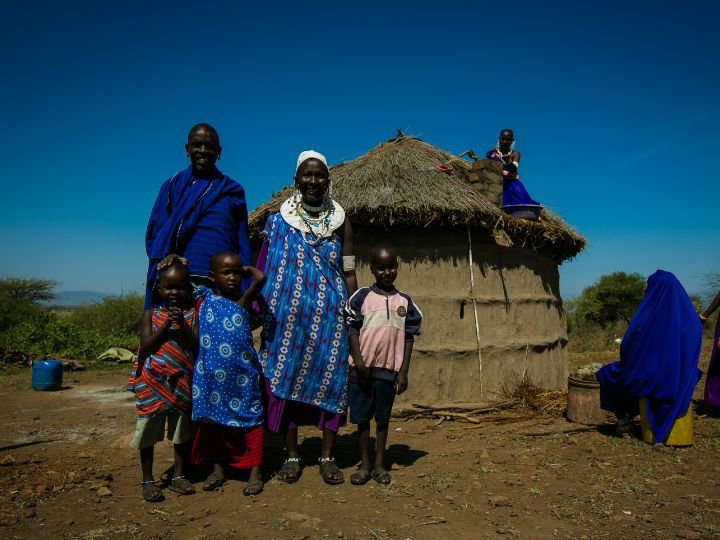 A family of five in colorful clothing stands in front of their home.