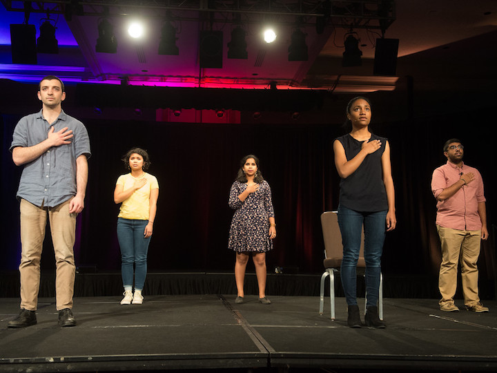 Students stand with their hands over their hearts while performing "I Pledge Allegiance"