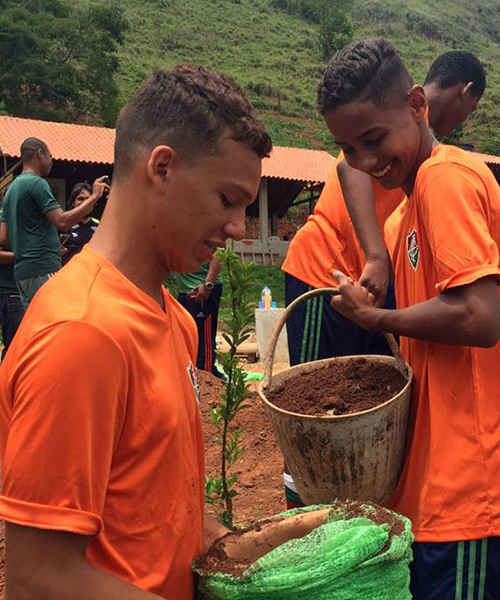 Two boys working together to plant a tree