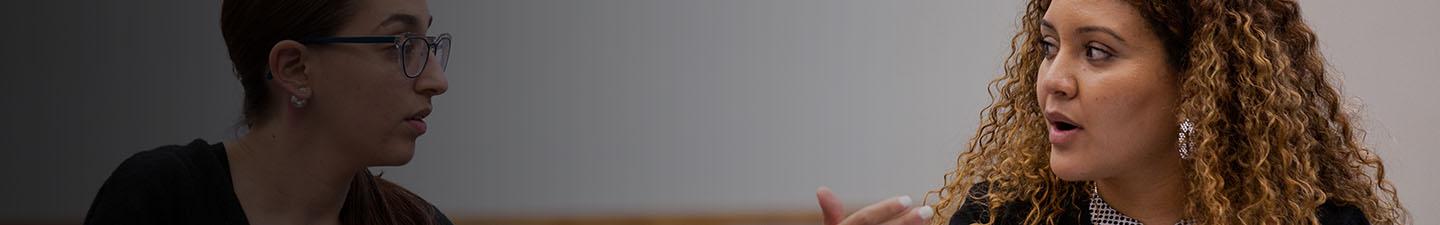 Una estudiante explicándole algo a otra estudiante