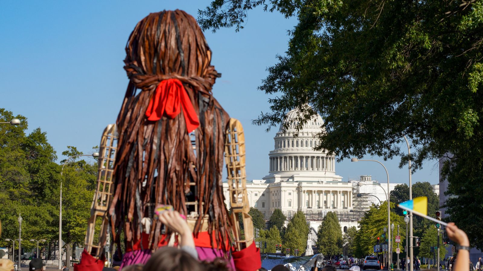 Amal, a puppet of a Syrian refugee girl, in front of the U.S. Capitol, surrounded by a crowd.