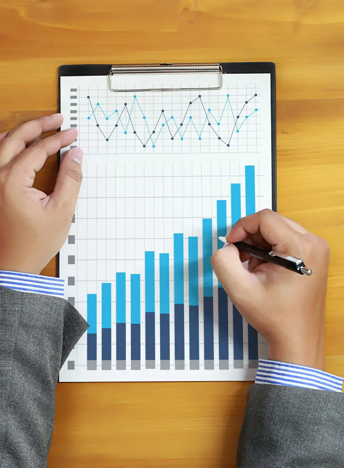 Hands reviewing data charts on a clipboard.