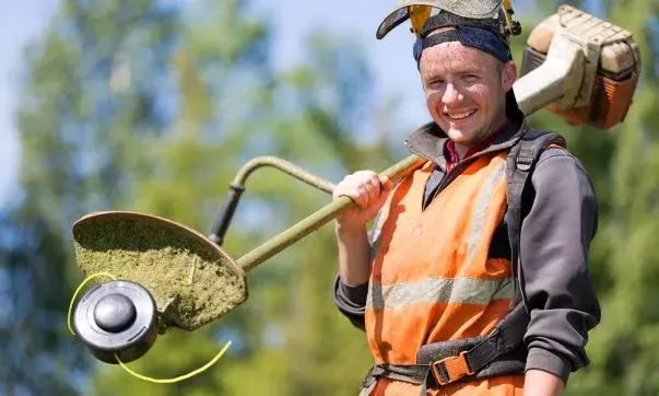 Landscaper working outdoors, using tools to maintain and enhance a property's lawn and garden.