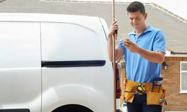 Plumber standing outside his work van, ready to assist with tools and equipment for the job.