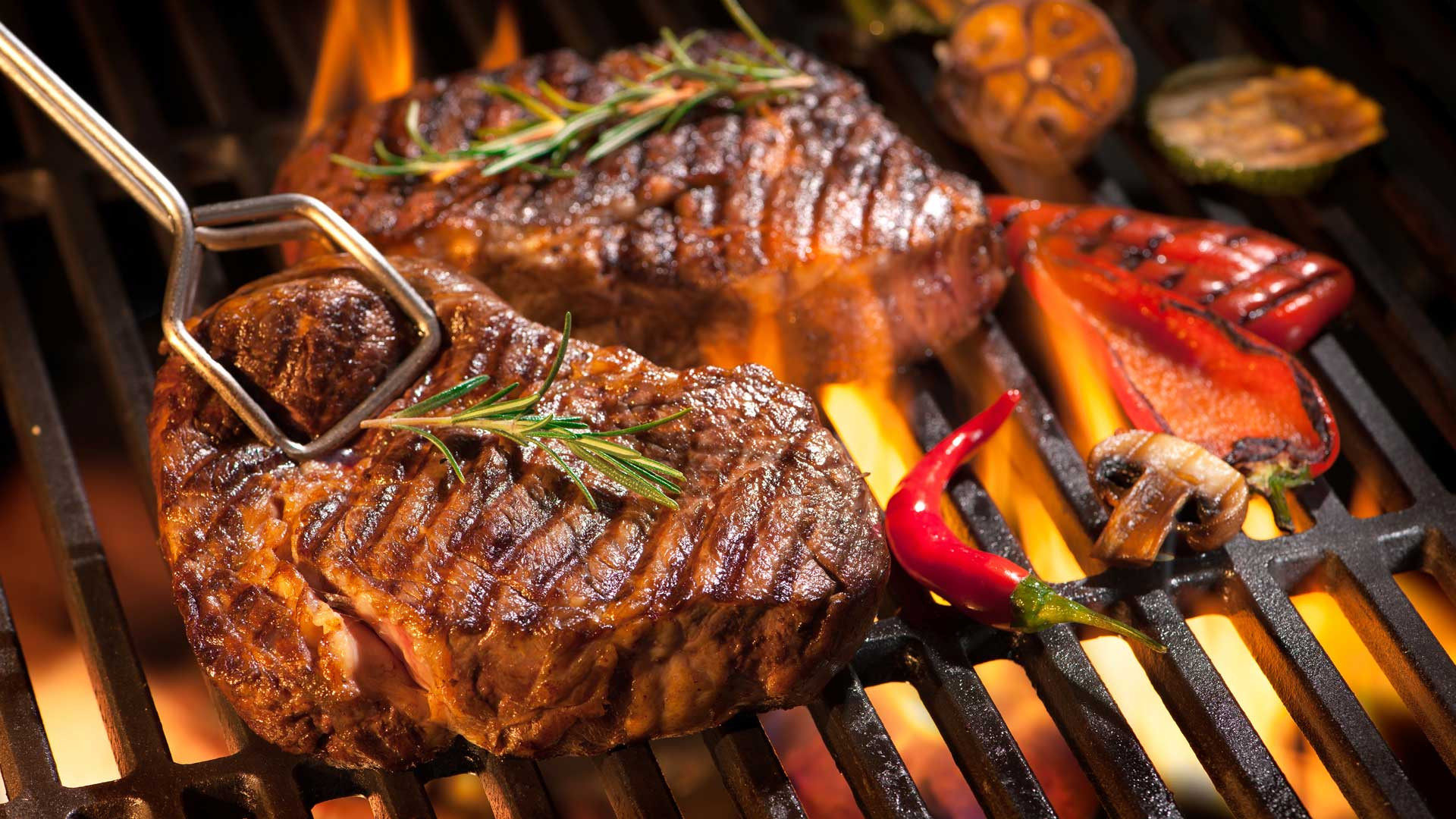 Grass-fed steaks searing over an open flame grill