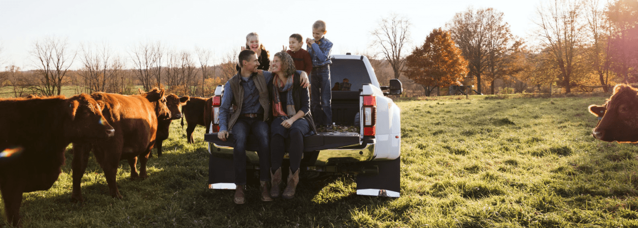 The Rosenberger-Ryan family in their farm pickup with cattle grazing nearby