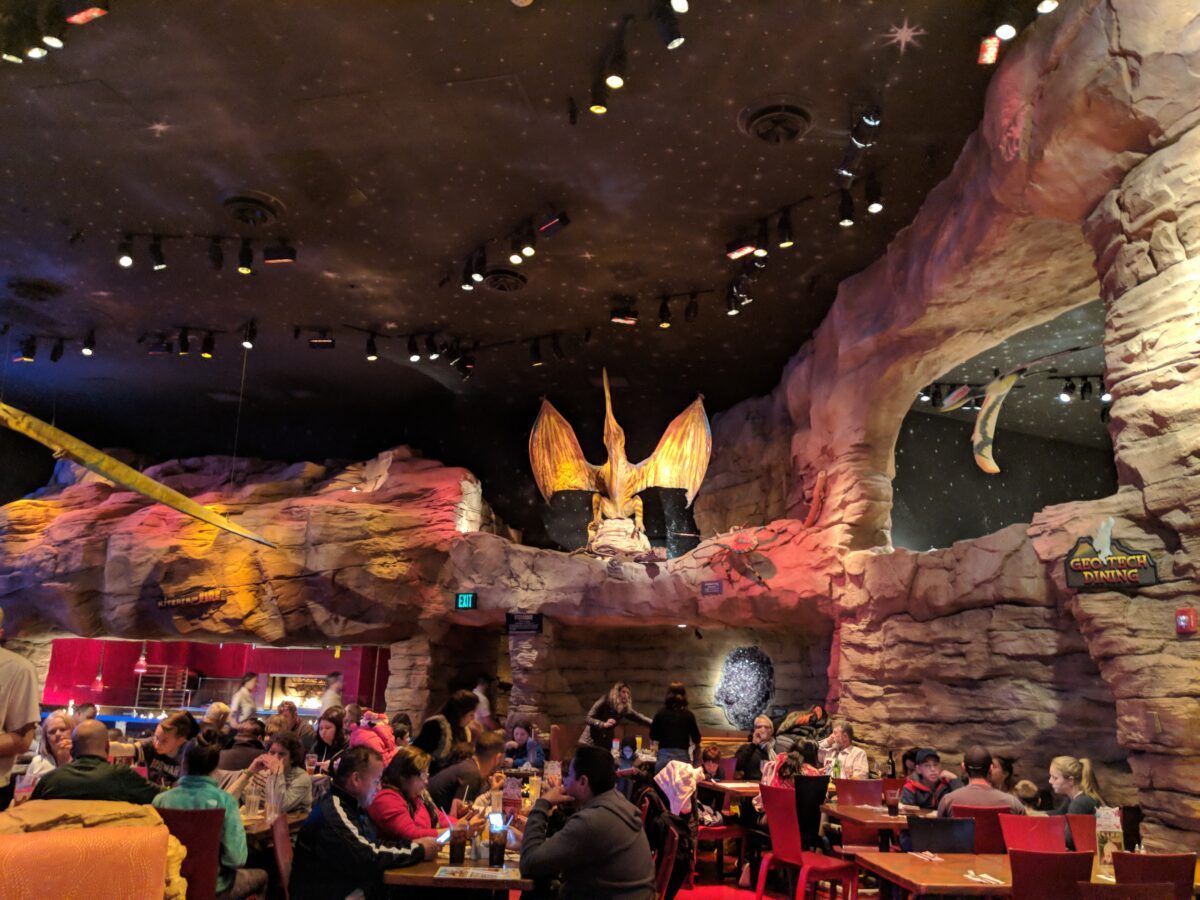 Inside T-Rex restaurant in Orlando Florida, guests eating at tables with model dinosaurs overhead