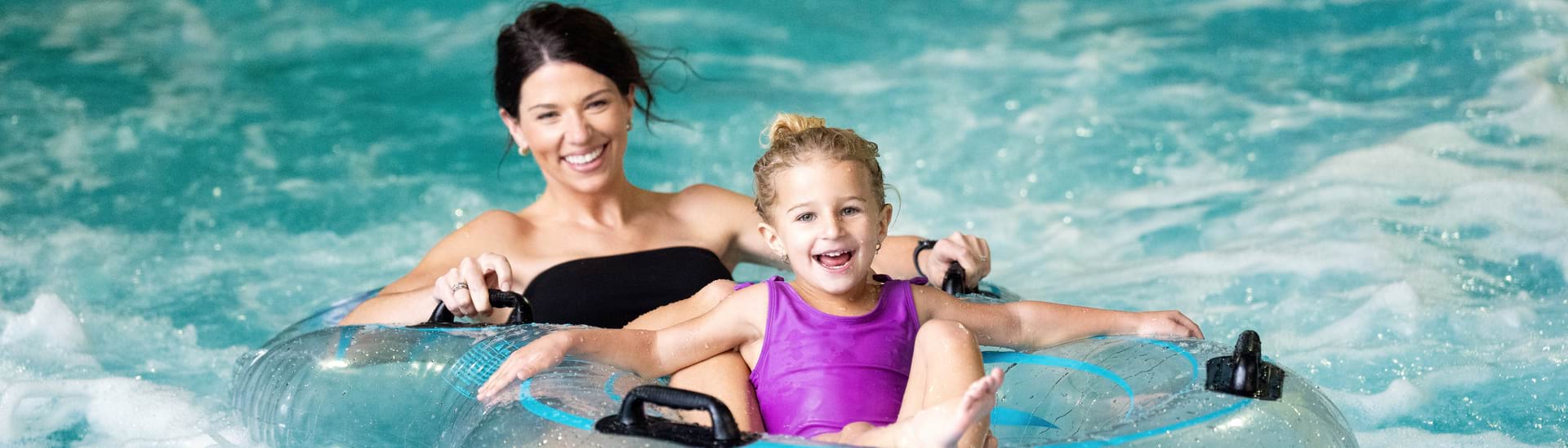 Beautiful girls riding pool game in an indoor waterpark at Timber Ridge Lodge