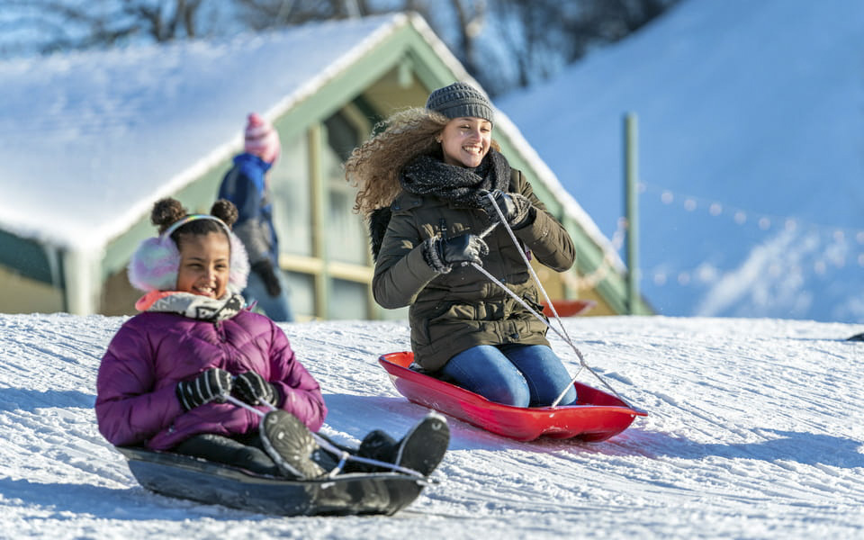 Two girls enjoying the sledding hill
