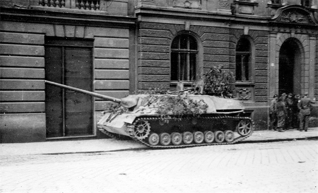 Německý těžký stíhač tanků Jagdpanzer IV v Komenského ulici v Olomouci. Vlevo jedni z posledních vojáků wehrmachtu ve městě. (květen 1945)