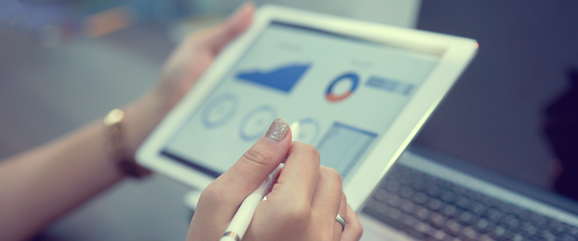 A person is holding a tablet that shows elements of a dashboard.