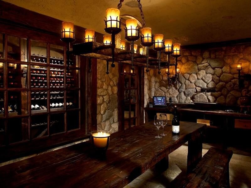CLWCTT Large wine tasting room design in stone and wood with one wall lined with custom wine storing cabinets.