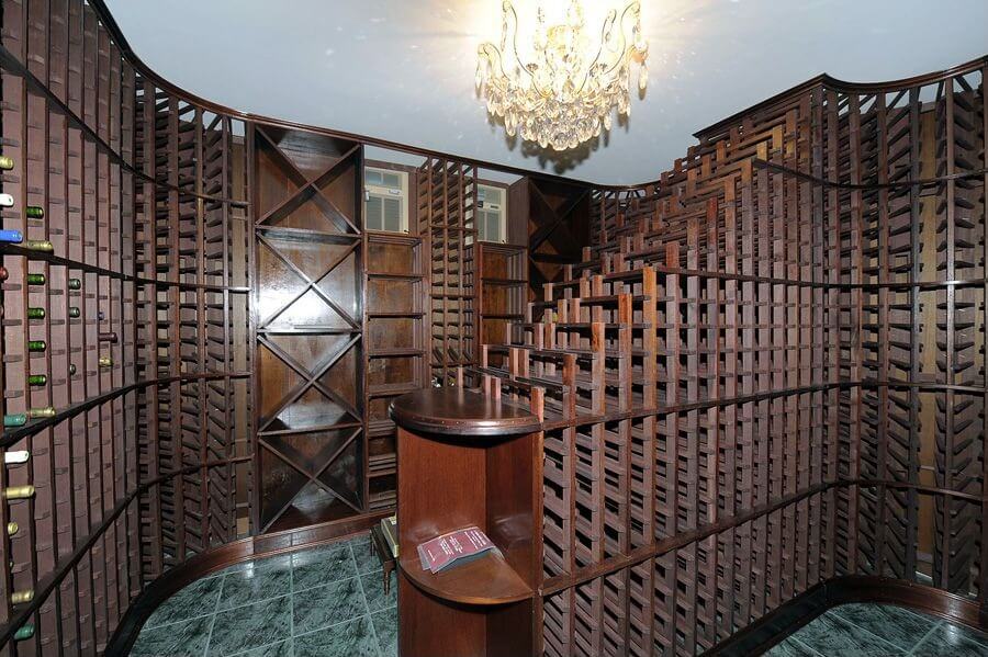 CLWCTT Wine cellar capable of storing thousands of bottles of wine in dark wood cabinets and green tile floor.