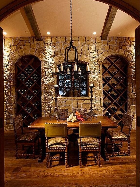 CLWCTT Ornate stone and wood wine cellar with exposed wood beamed ceiling and tasting table for six people.