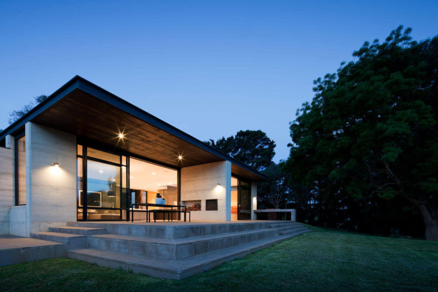 The foundation extends onto this tiered patio, with steps leading down to gently sloping lawn. Floor to ceiling glass under the large eaves allow indirect lighting throughout. The foundation extends onto this tiered patio, with steps leading down to gently sloping lawn. Floor to ceiling glass under the large eaves allow indirect lighting throughout.