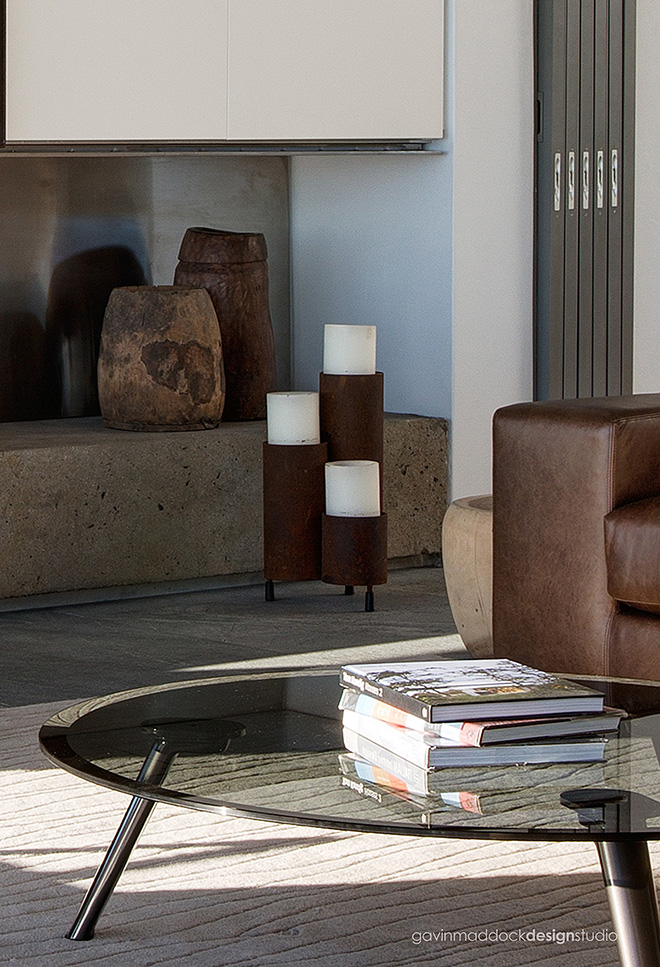 Close detail in the living room highlights the modern glass and steel coffee table and, in background, the retractible glass panels hidden within the wall. Close detail in the living room highlights the modern glass and steel coffee table and, in background, the retractible glass panels hidden within the wall.