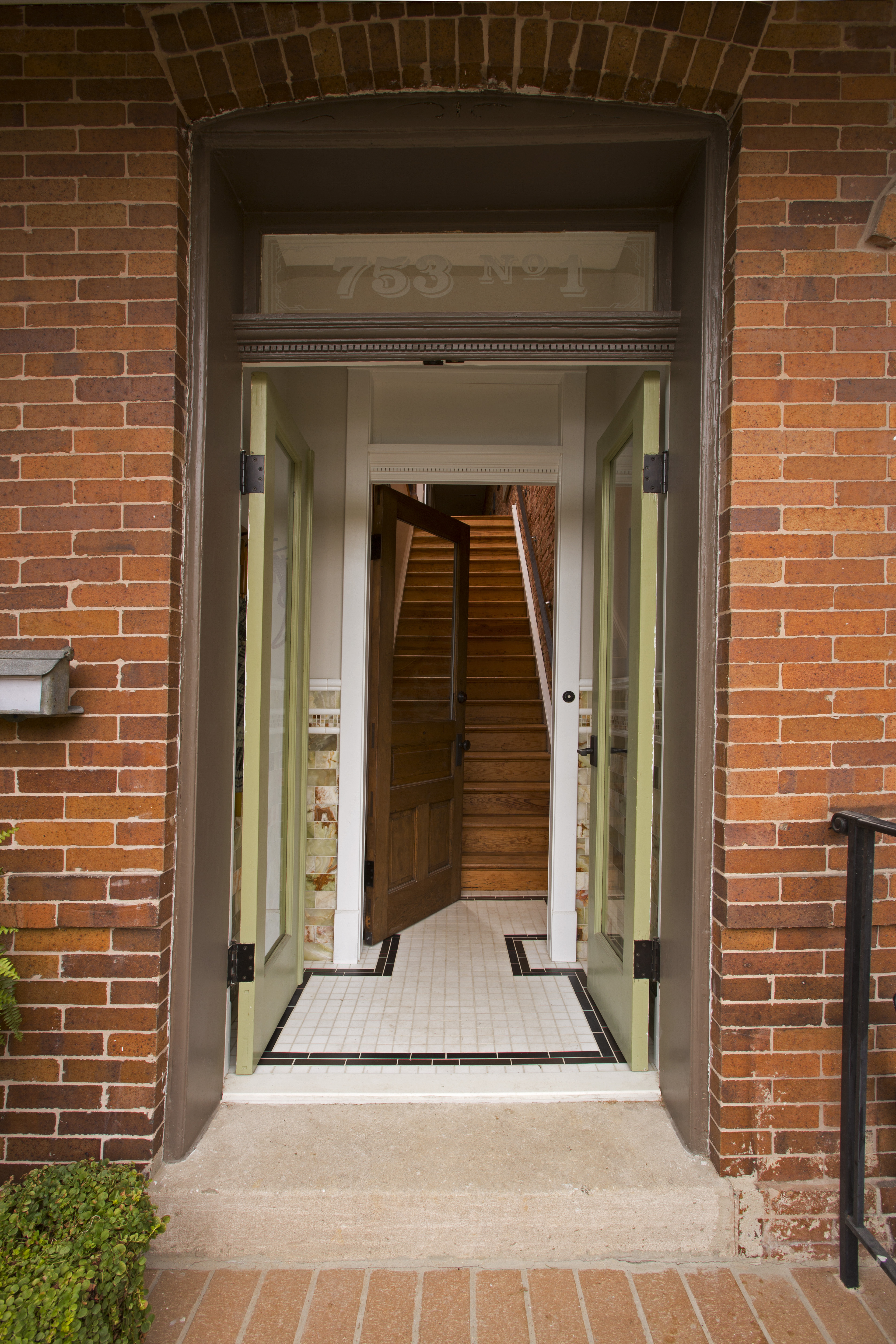 The green double doors lead into the main hardwood staircase to the first of the two condos. The green double doors lead into the main hardwood staircase to the first of the two condos.
